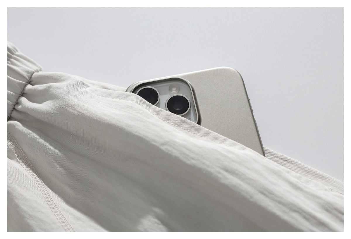 Close-up showing a smartphone tucked into a pocket on cream-colored bottoms.