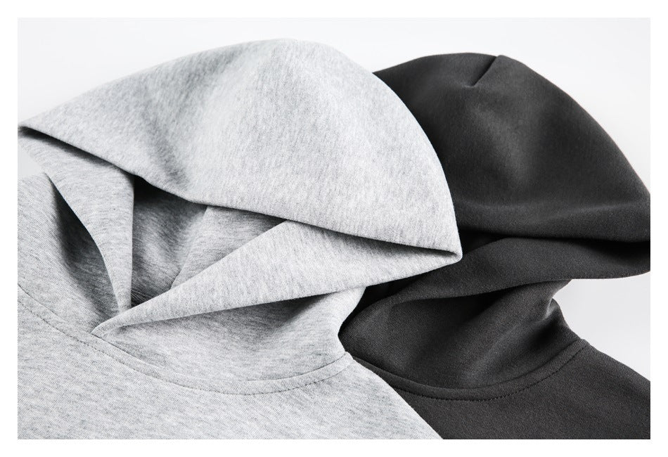 Close-up of overlapping light gray and dark hoodies, showing their hoods and neckline seams.