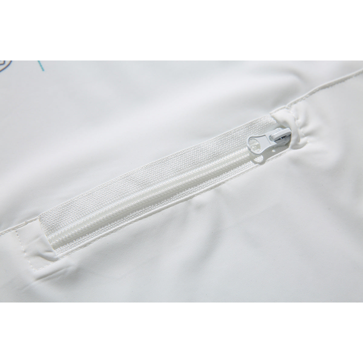 Close-up of a white zipper and stitching set into white garment fabric.