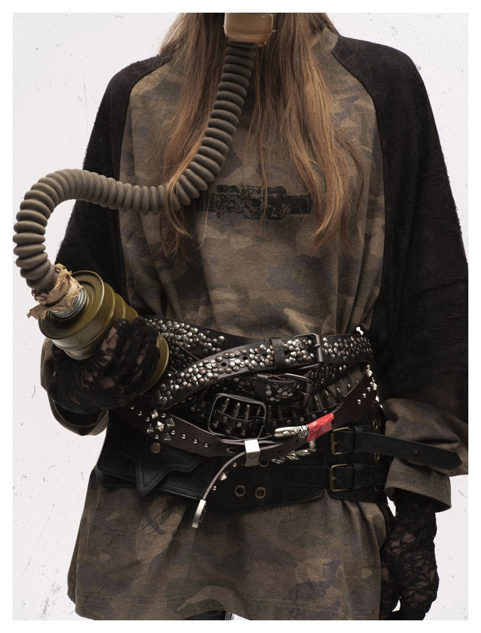 Close-up of the camouflage shirt's front, black raglan sleeves and layered studded belts.