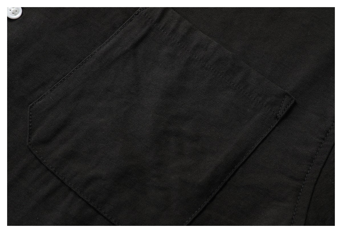 Close-up of a large stitched pocket on a black shirt.