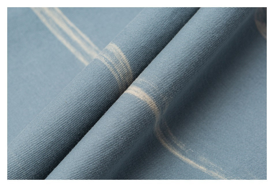 Close-up of pale blue shirt fabric folded to show its weave and white streak pattern.