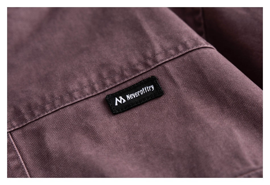 Close-up of a black sewn label on muted plum fabric.