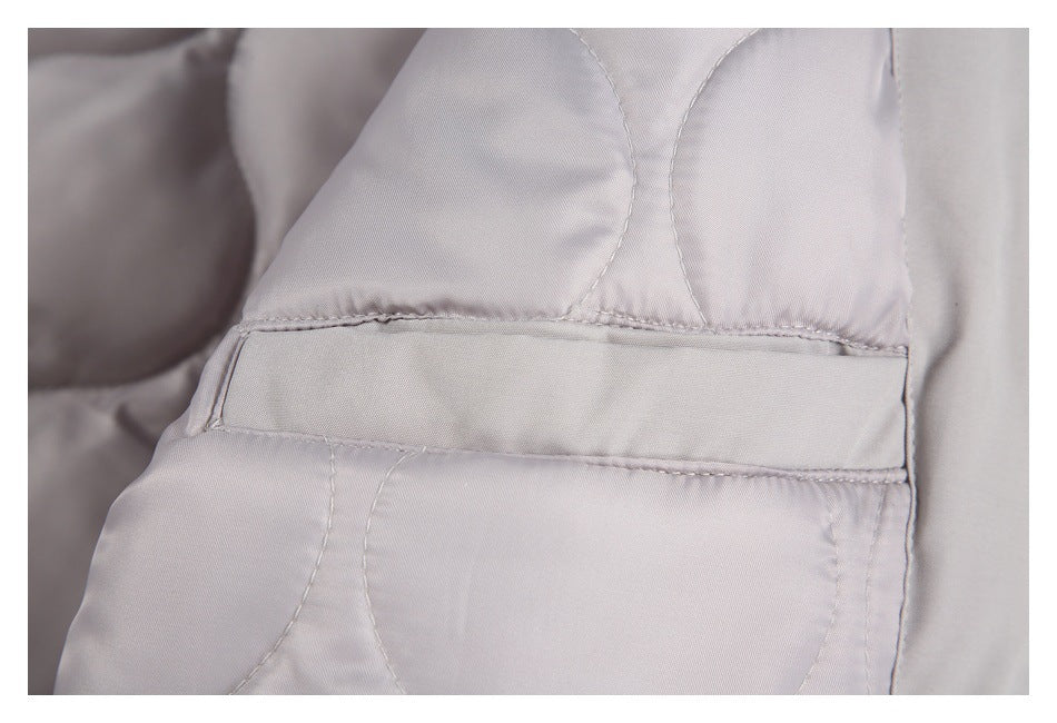 Close-up of a light gray jacket’s stitched pocket opening and quilted lining.