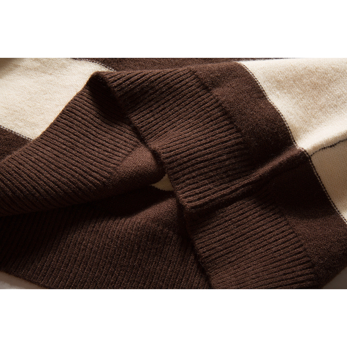 Close-up of a wide brown ribbed sweater cuff against brown and cream striped knit.