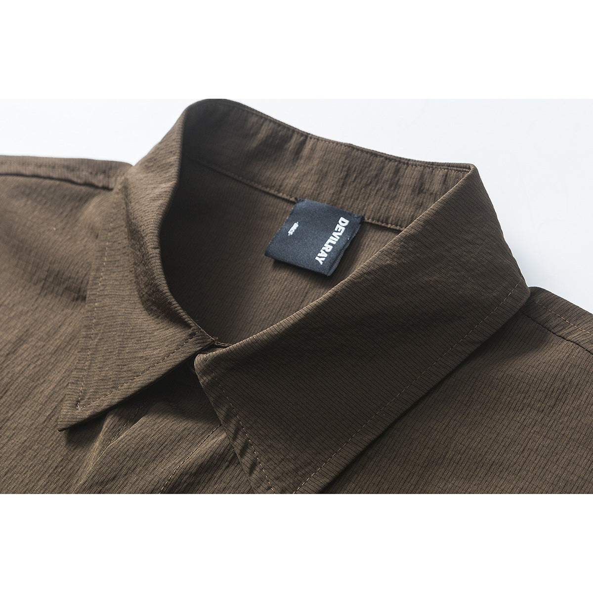 Close-up of a dark brown finely striped shirt collar with a black sewn-in label.