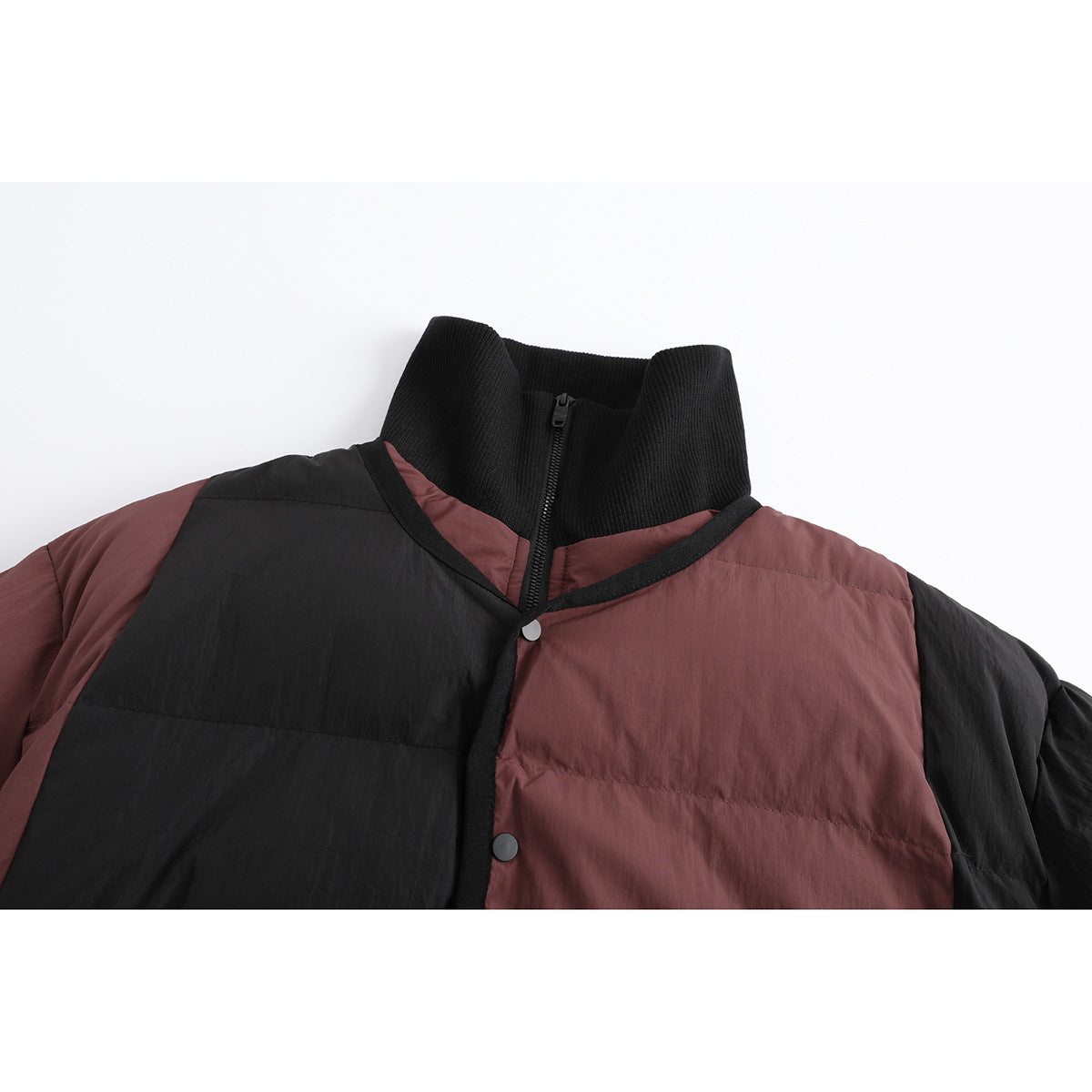 Close-up of a black and burgundy quilted jacket collar, zipper, snap, and contrasting front panels.