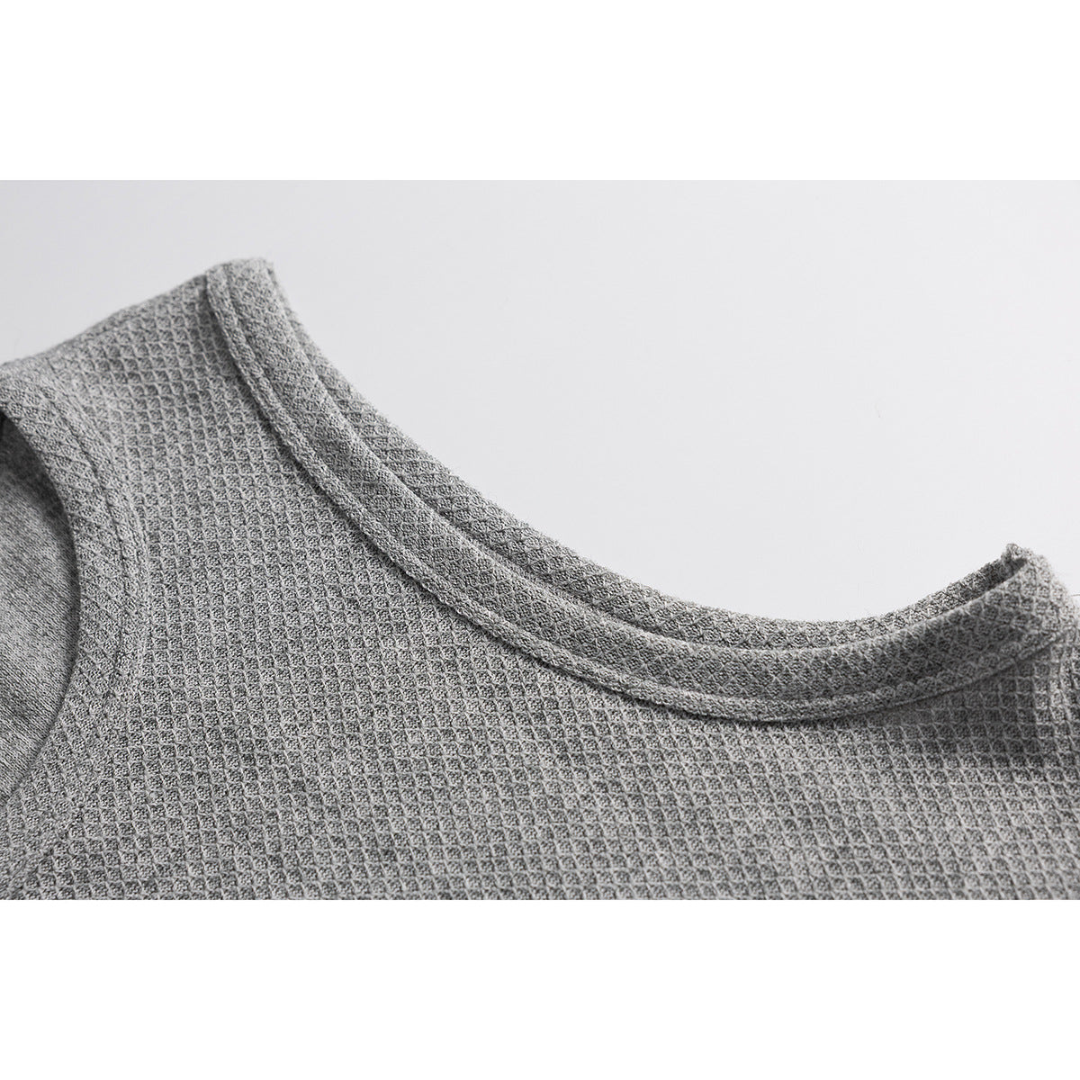 Close-up of the bound crew neckline and textured knit of a gray sleeveless top.