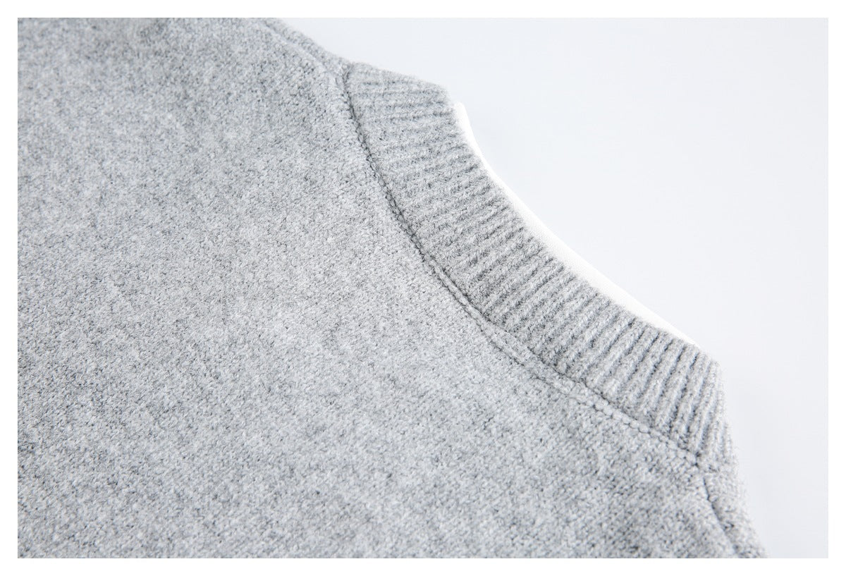 Close-up of a light gray knit garment showing a ribbed neckline and joining seam.