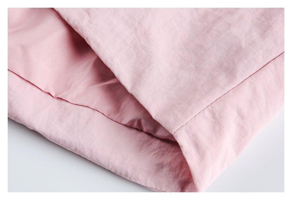 Close-up of folded pale pink jacket fabric and stitched hem seams.