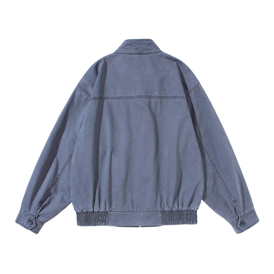 Back view of a dusty blue jacket with a stand collar, seam detailing, buttoned cuffs, and an elasticated hem.