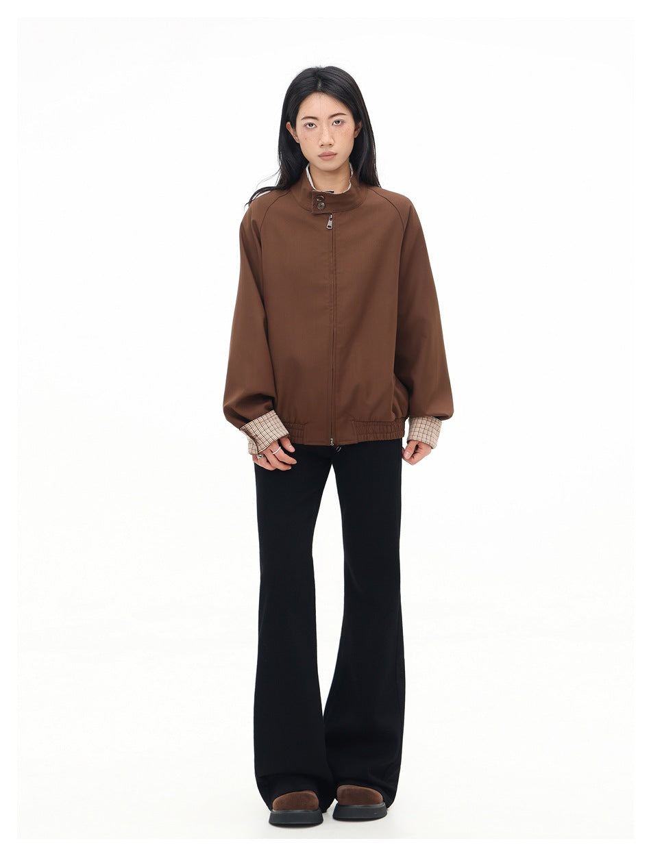 Full-length front view of a model wearing a brown zip-front jacket with plaid cuffs and black flared pants.