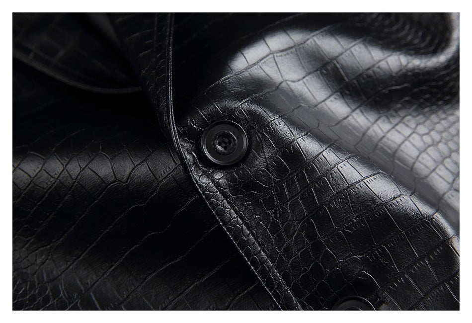 Close-up of a black button and glossy crocodile-textured fabric on the jacket front.