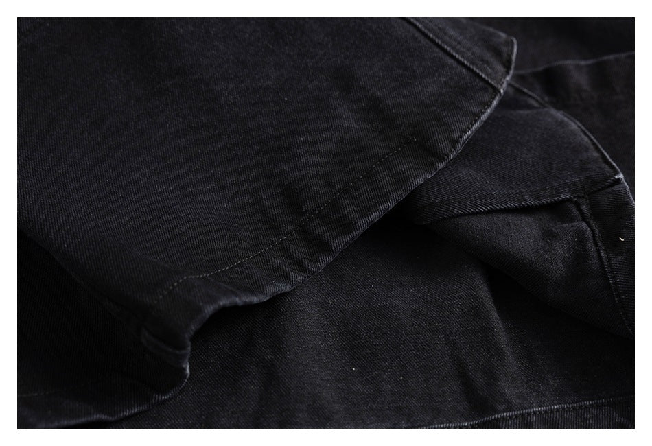 Close-up of black twill fabric with overlapping stitched garment panels.