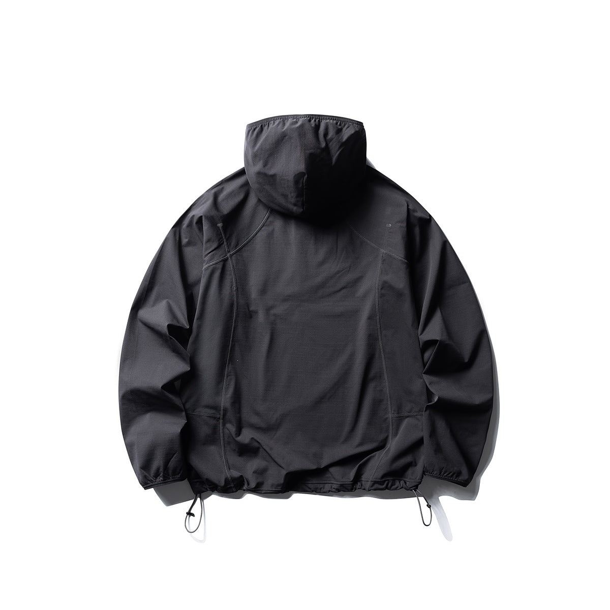 Back view of a black hooded jacket with curved seams and adjustable drawcord hem, laid flat on white.