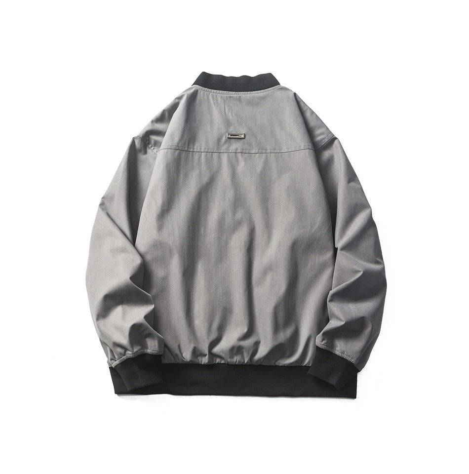 Back view of a gray bomber jacket with black ribbed collar, cuffs, and hem and a small metal badge.