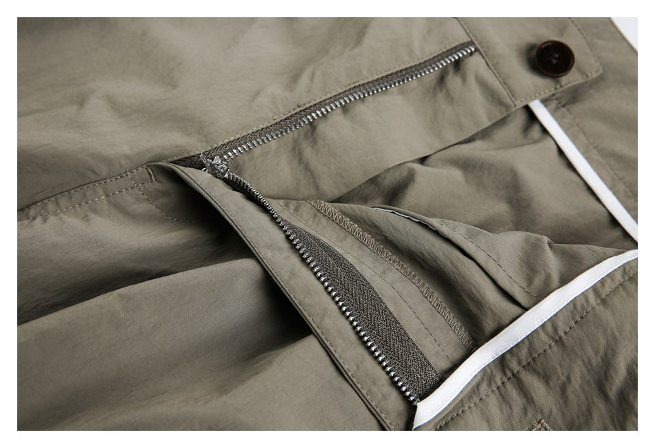 Close-up of olive-gray trousers with the metal fly zipper open, revealing the inner placket.