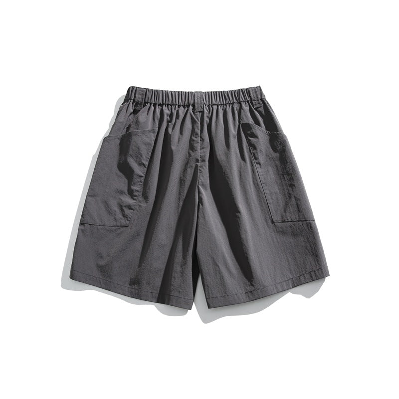Dark gray shorts with an elastic waistband and large patch pockets on both sides, shown against white.