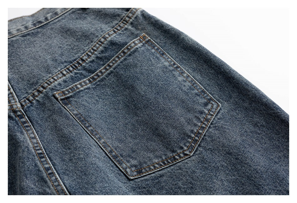 Close-up of a stitched back patch pocket on blue-gray jeans.