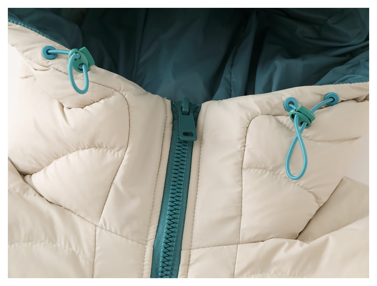 Close-up of the teal-lined hood opening, drawcord toggles, and zipper on an ivory quilted jacket.