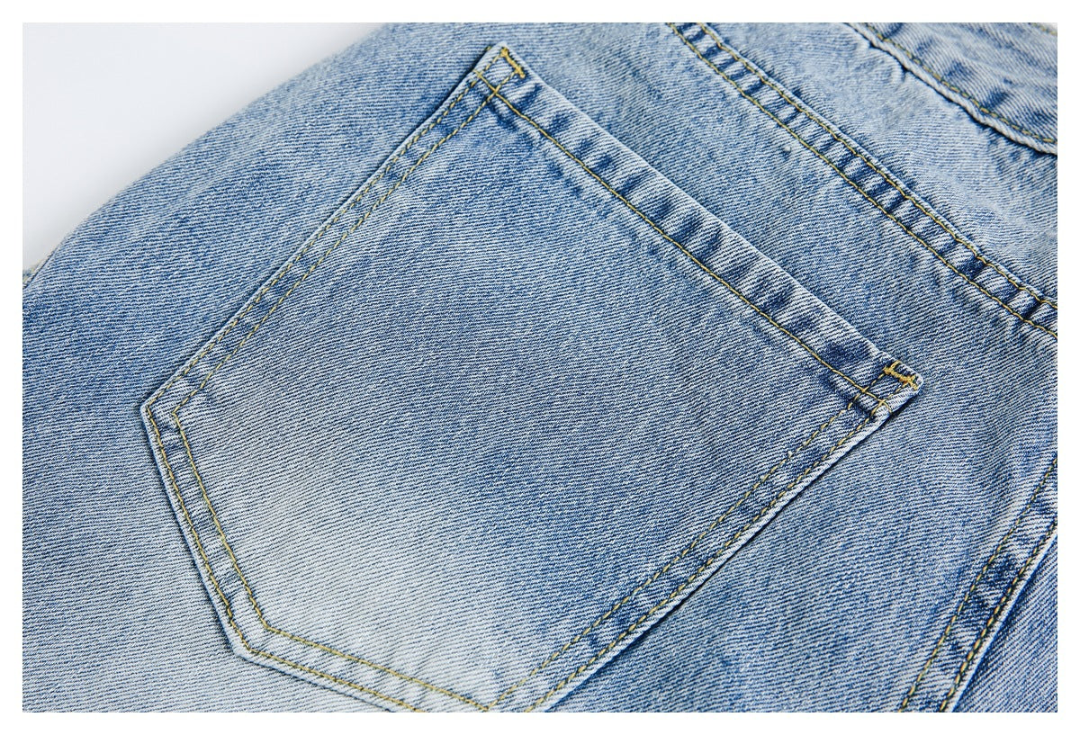 Close-up of a rear patch pocket on light blue jeans with contrasting yellow stitching.