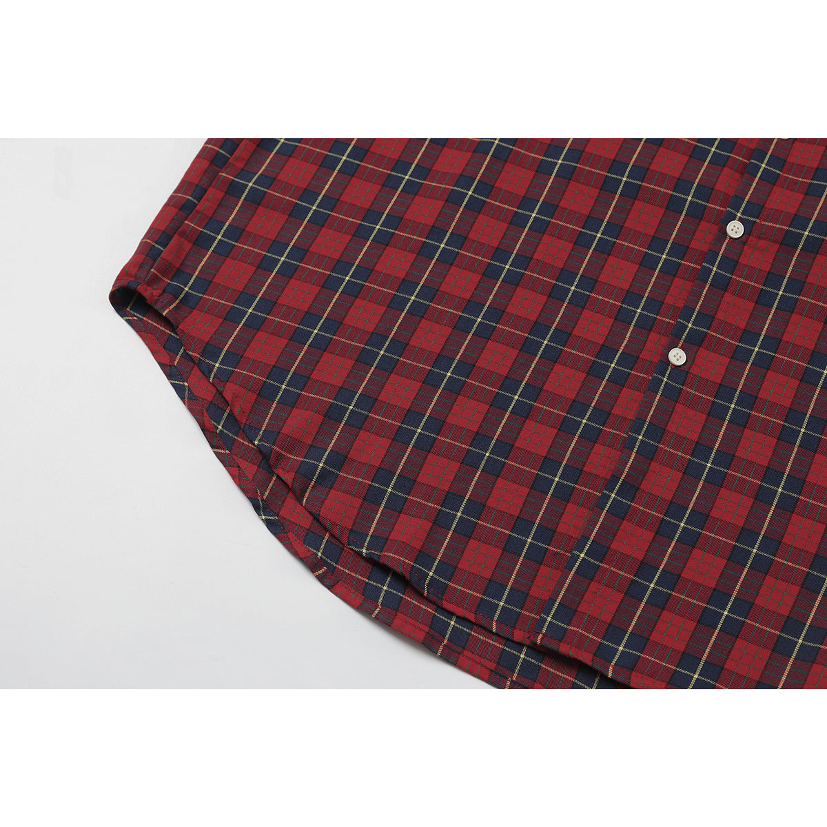 Close-up of the red and navy plaid shirt's front buttons, side seam, and curved hem.