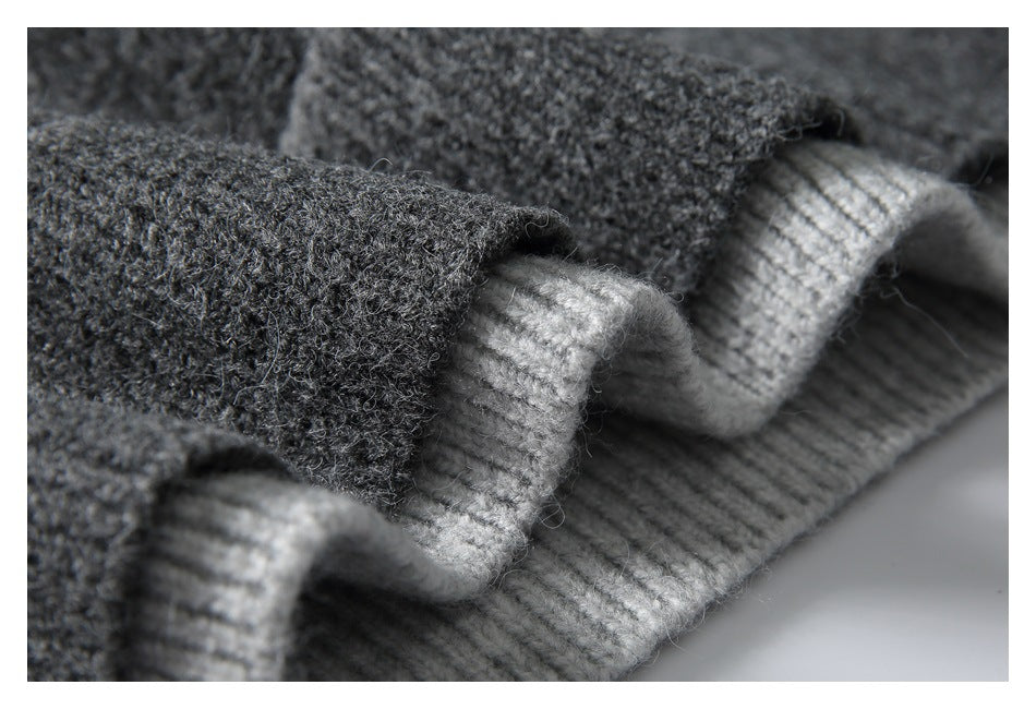 Close-up of dark charcoal fuzzy knit fabric with a lighter gray ribbed edge folded over it.