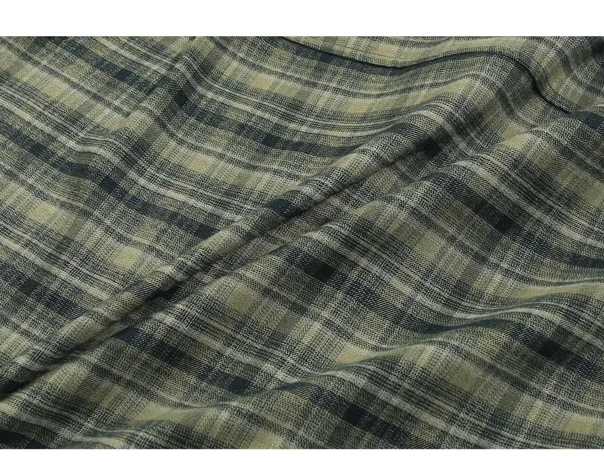 Close-up of gathered olive, charcoal, and beige plaid fabric showing a fine woven texture.