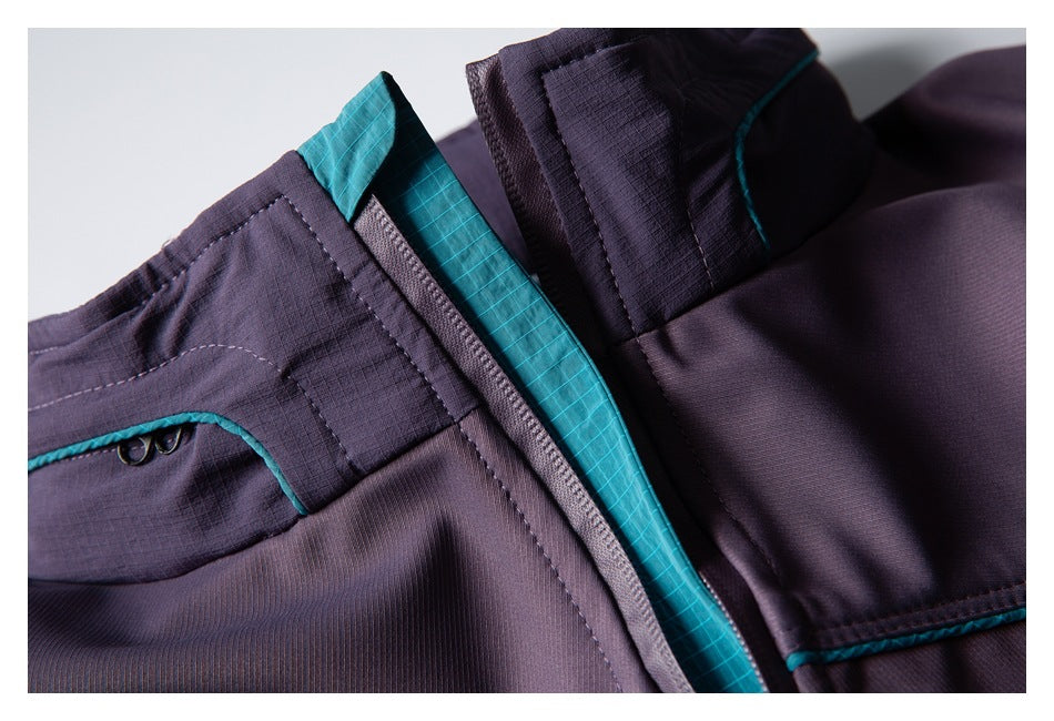 Close-up of a plum jacket front zipper, teal lining, and stitched panels.