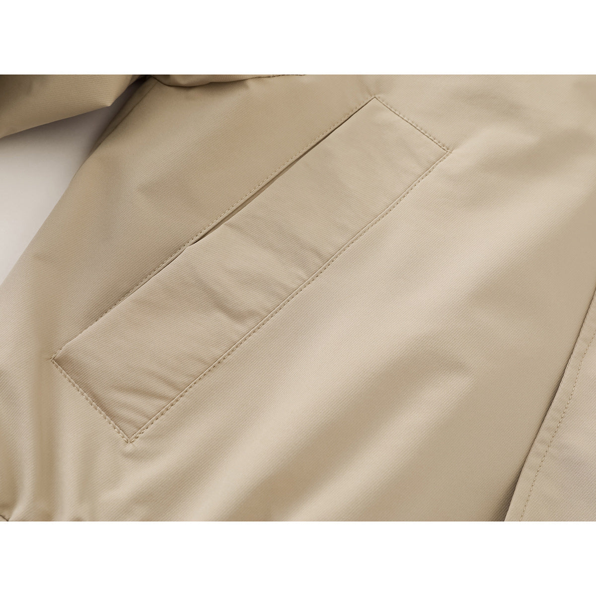 Close-up of a beige jacket’s stitched diagonal front placket and concealed fastening.