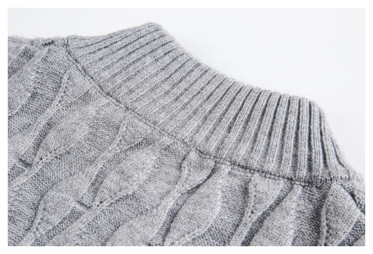 Close-up of a gray cable-knit sweater showing its ribbed neckline and raised knit pattern.