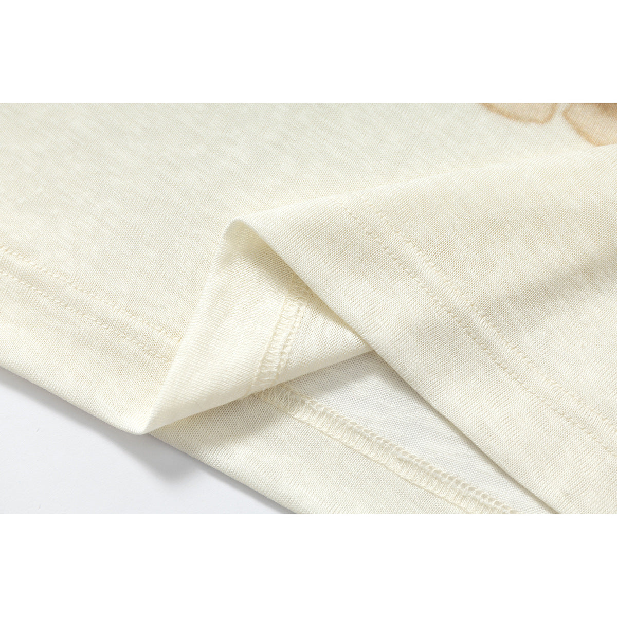 Close-up of the ivory shirt's folded hem and stitching.