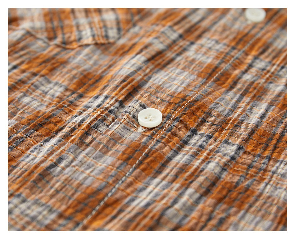 Close-up of an ivory button on orange, gray, and cream plaid fabric.