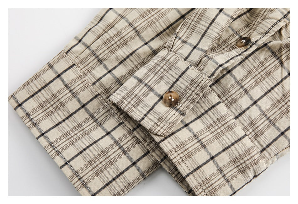 Close-up of a buttoned flap and seam on a beige garment with black and brown plaid.