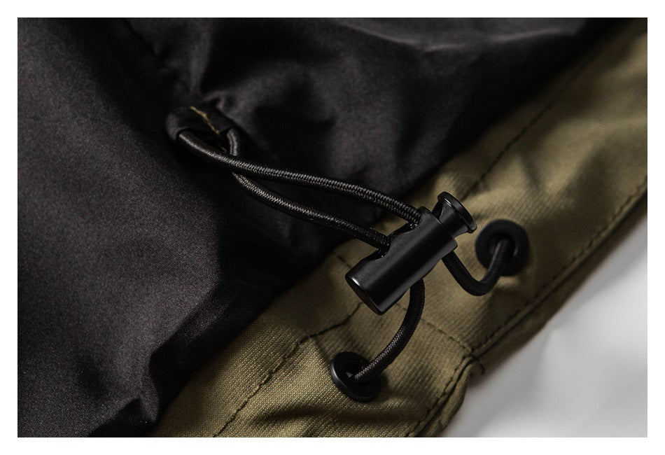 Close-up of a black drawcord and toggle at the olive jacket hem beside its dark lining.
