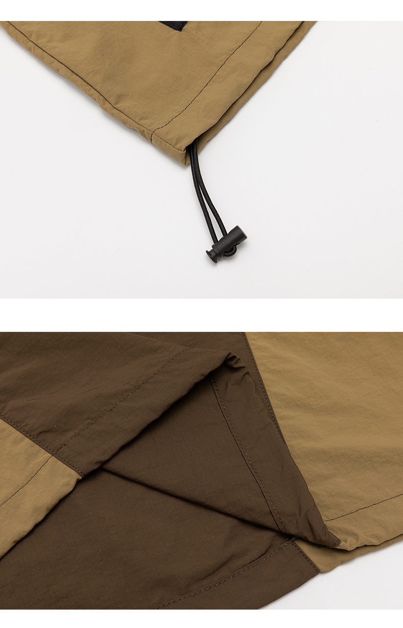 Close-up of a tan jacket hem with a black adjustable drawcord and layered brown and tan panels.