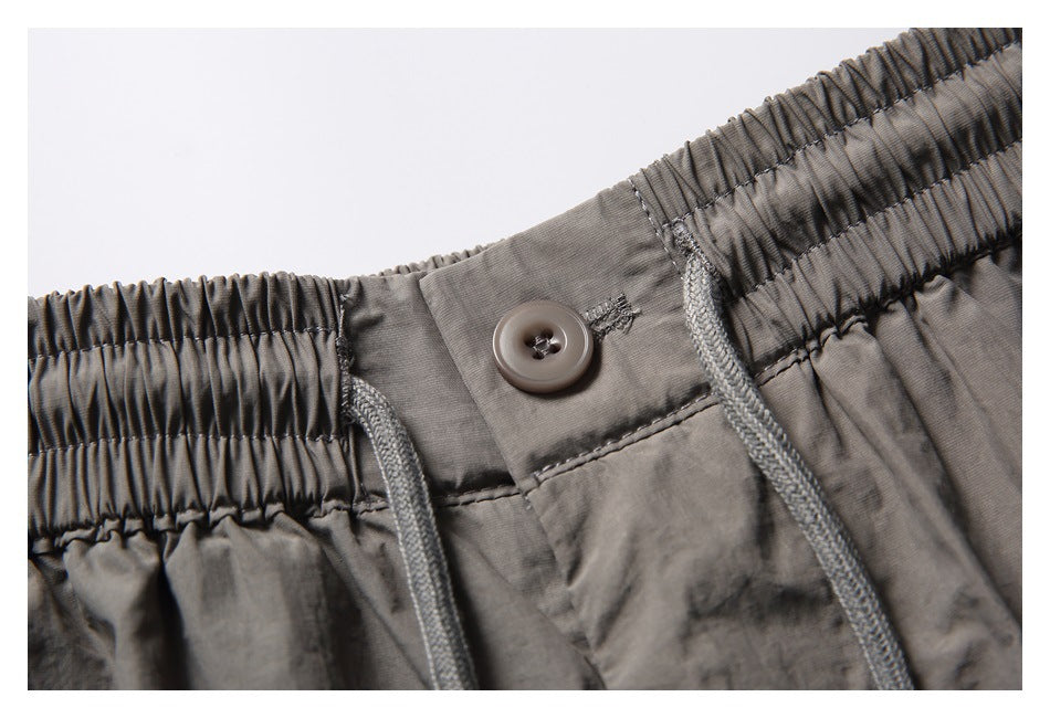 Close-up of a gray button at the elastic waistband and the drawstrings.