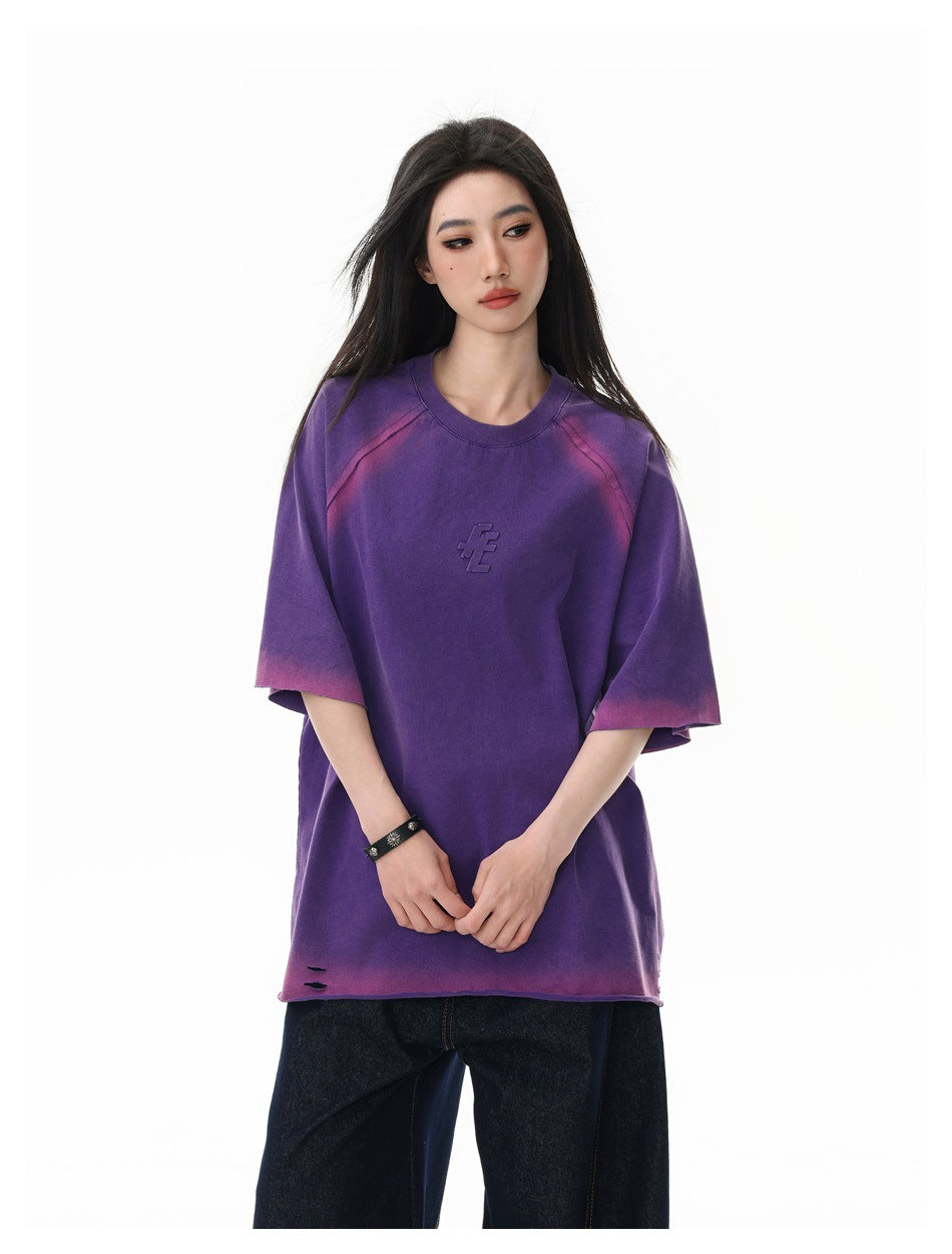 Close-up of model wearing the purple raglan T-shirt showing pink gradient sleeves, embossed chest graphic and hem slits