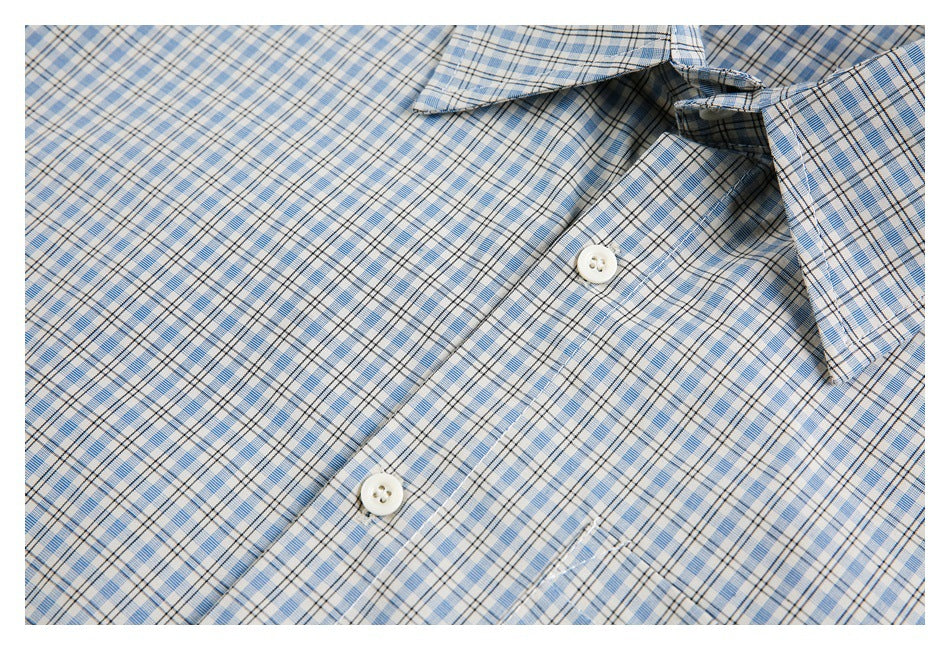 Close-up of a blue plaid button-up shirt showing its collar, placket, white buttons, and chest pocket.