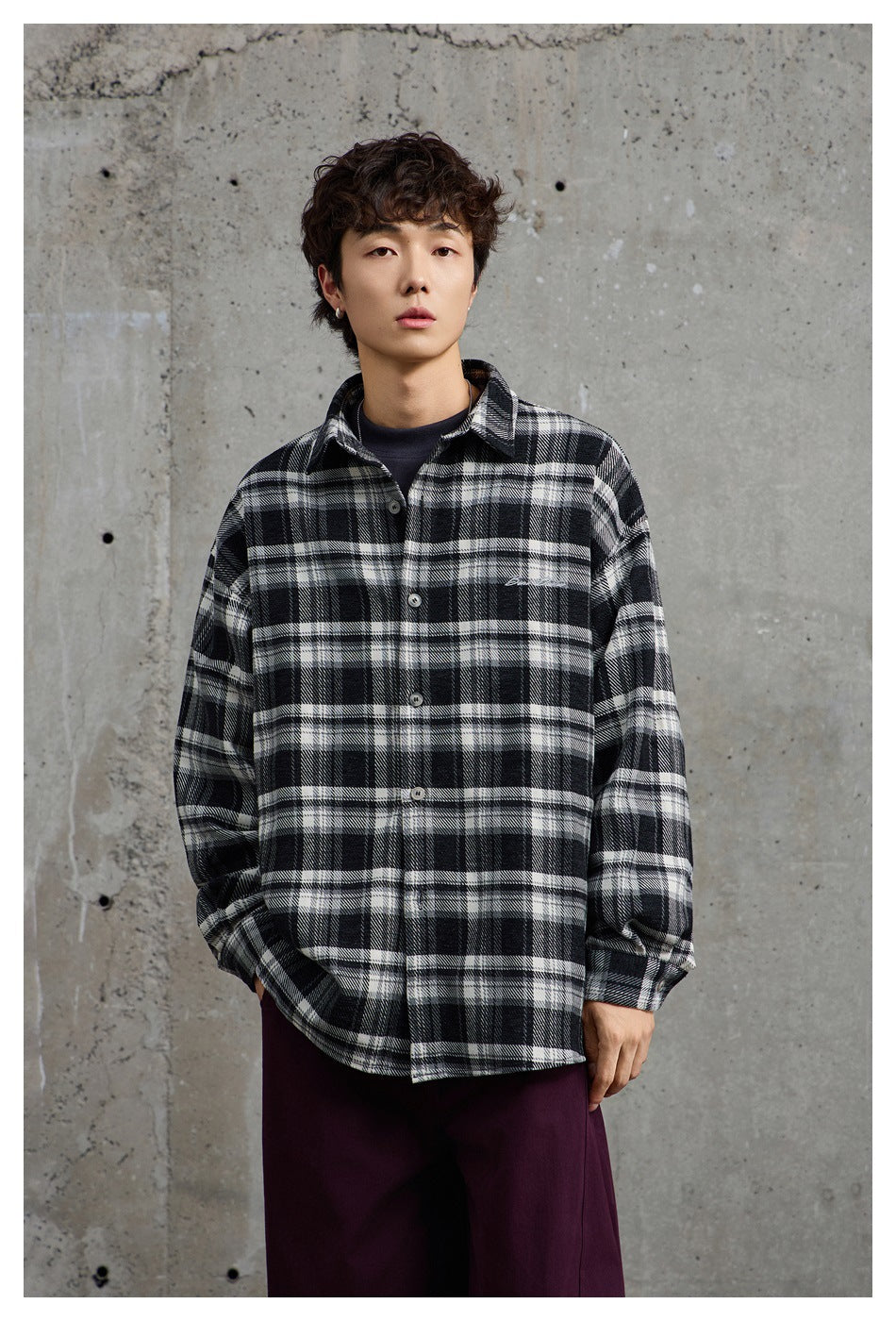 Model wearing a black, gray, and white plaid button-up shirt over a dark top.