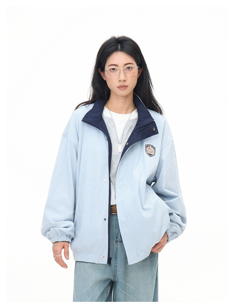Closer front view of a model wearing a pale blue jacket with a navy collar, snap closures and a chest crest.