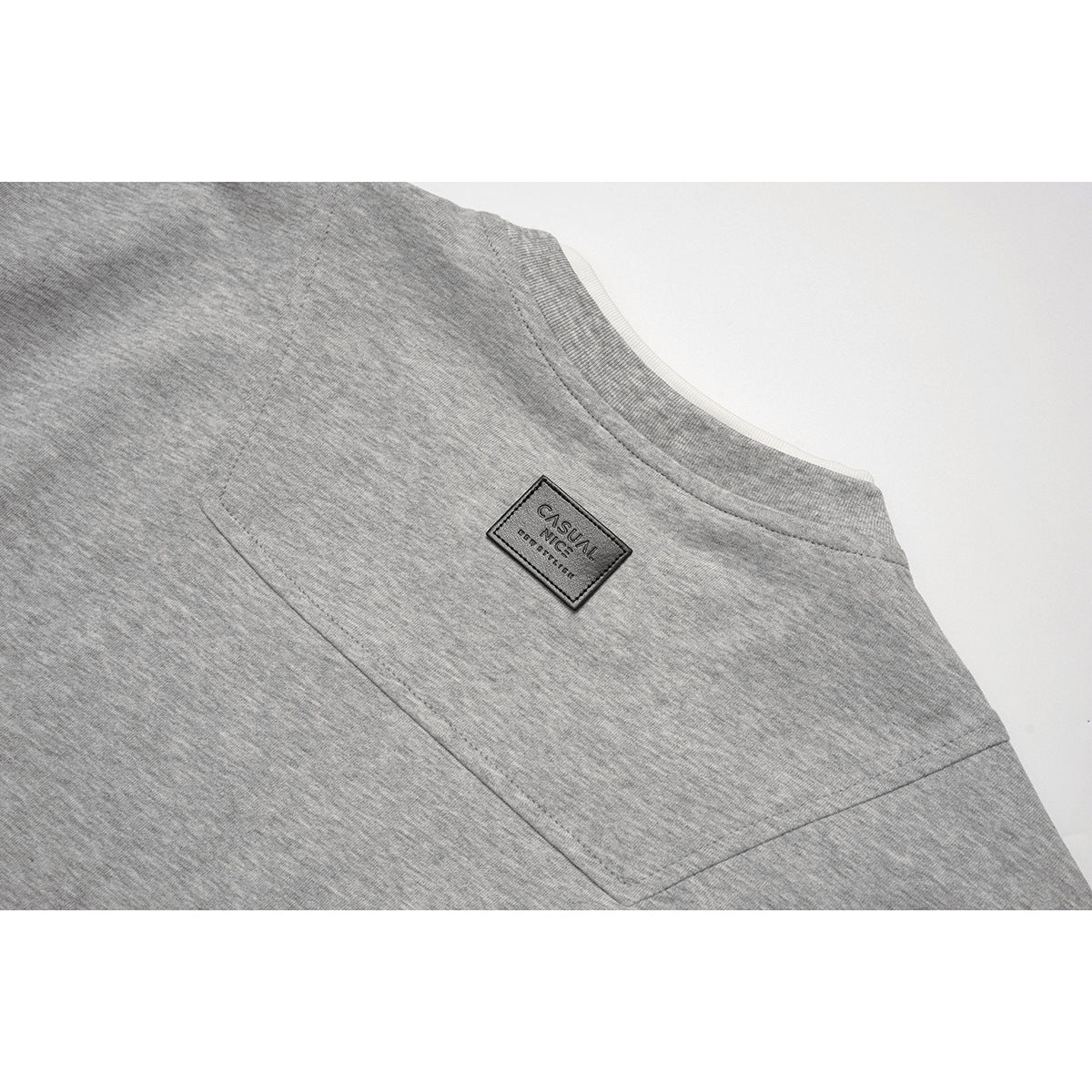 Close-up of the heather gray sweatshirt’s back shoulder seam and small sewn label.