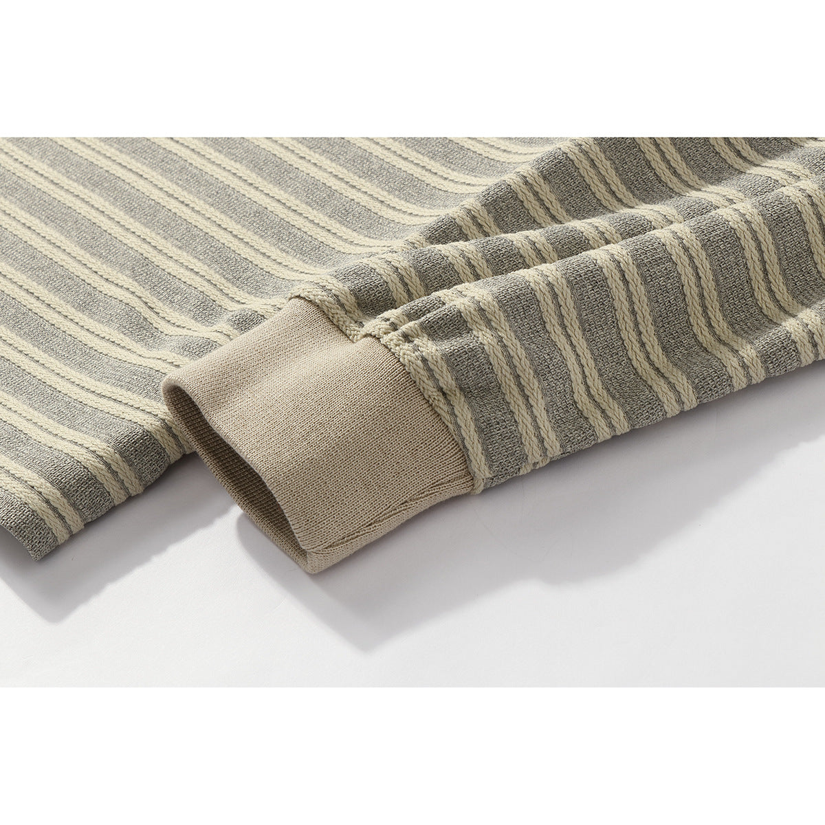 Close-up of a beige ribbed cuff on a gray and cream striped sleeve.
