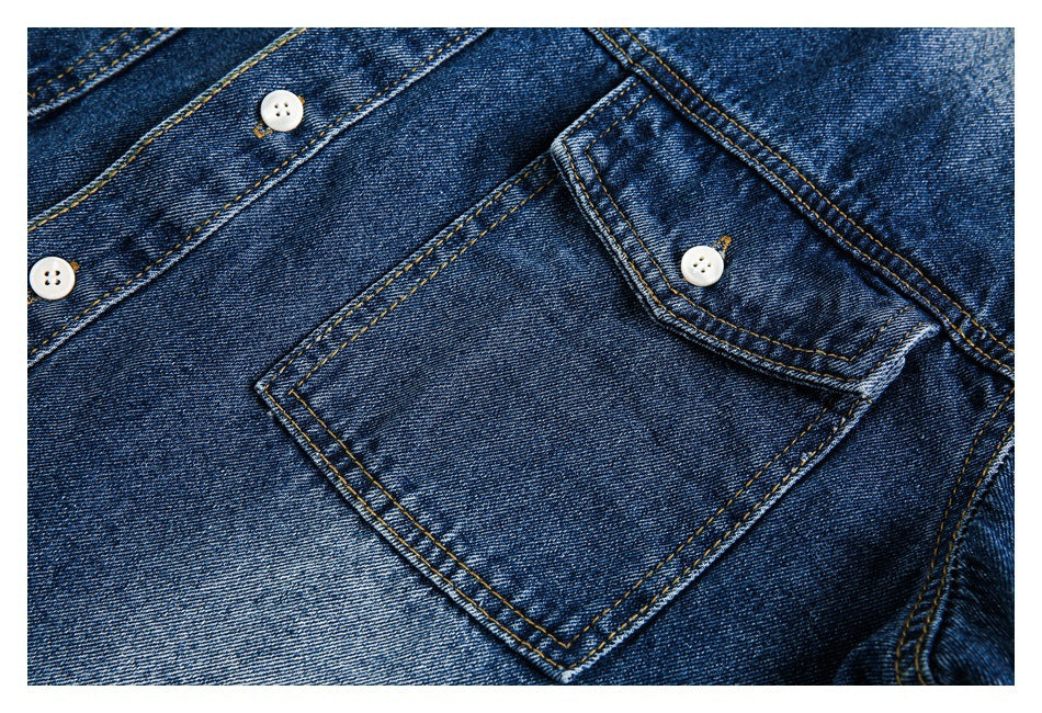 Close-up of a dark blue denim shirt pocket flap, pocket seams, and white buttons.
