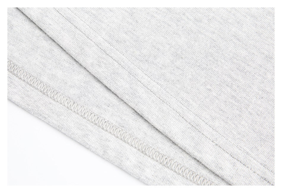 Close-up of a heather gray garment showing a stitched hem and overlock seam.