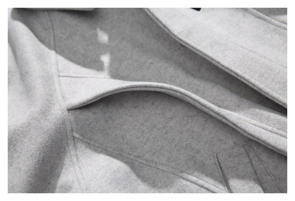 Close-up of a light gray garment showing overlapping panels, curved piping, and stitched seams.