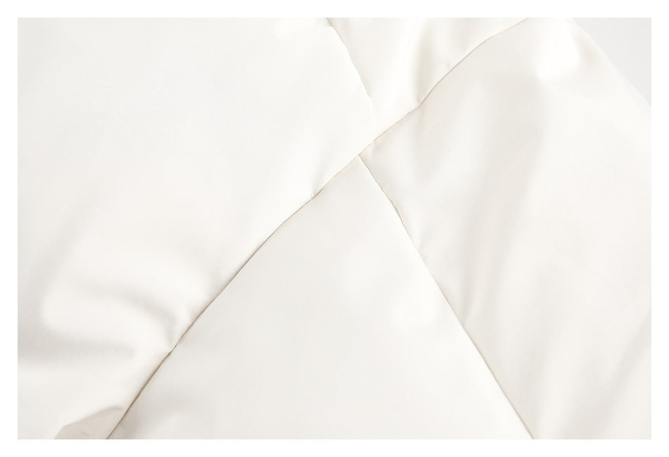 Close-up of off-white garment panels meeting at diagonal stitched seams.