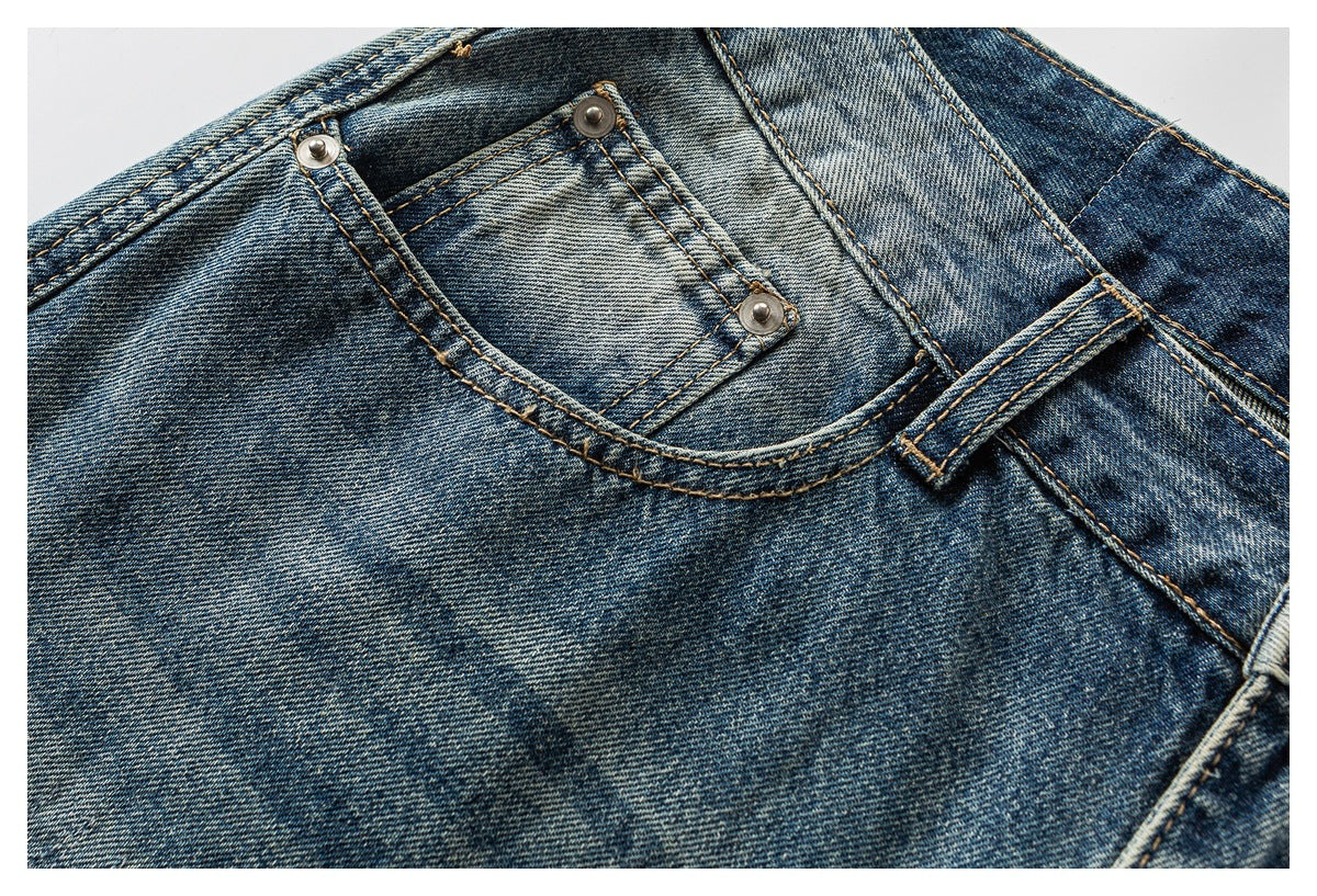 Close-up of faded blue jeans showing a curved front pocket, small coin pocket, and metal rivets.