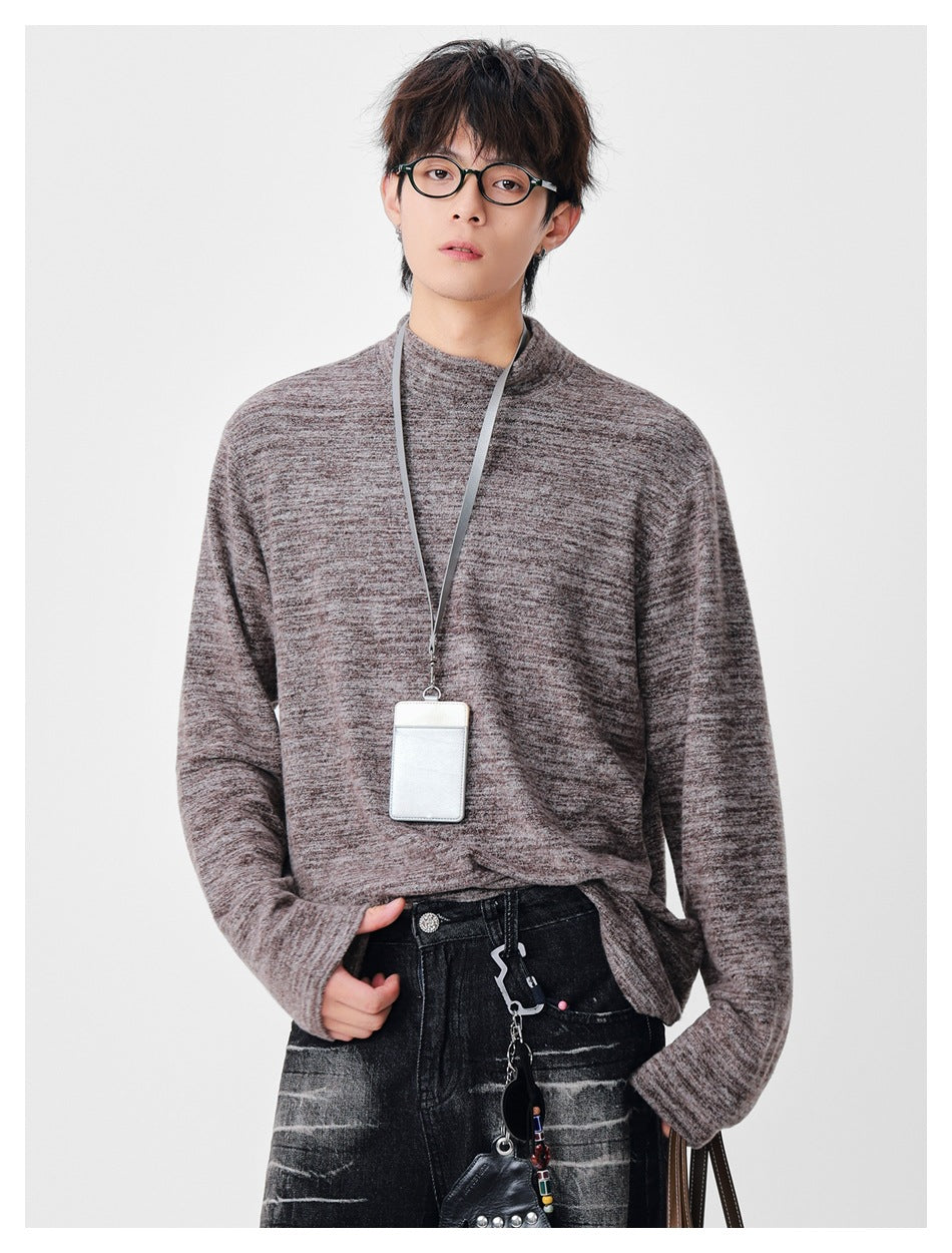 Model wearing a brown marled mock neck long-sleeve top, one hand in pocket, with a lanyard