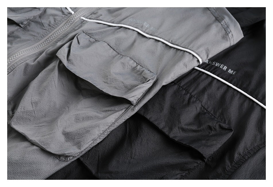 Close-up of gray and black jackets showing flap pockets, white piping, and small “ANSWER ME” lettering.